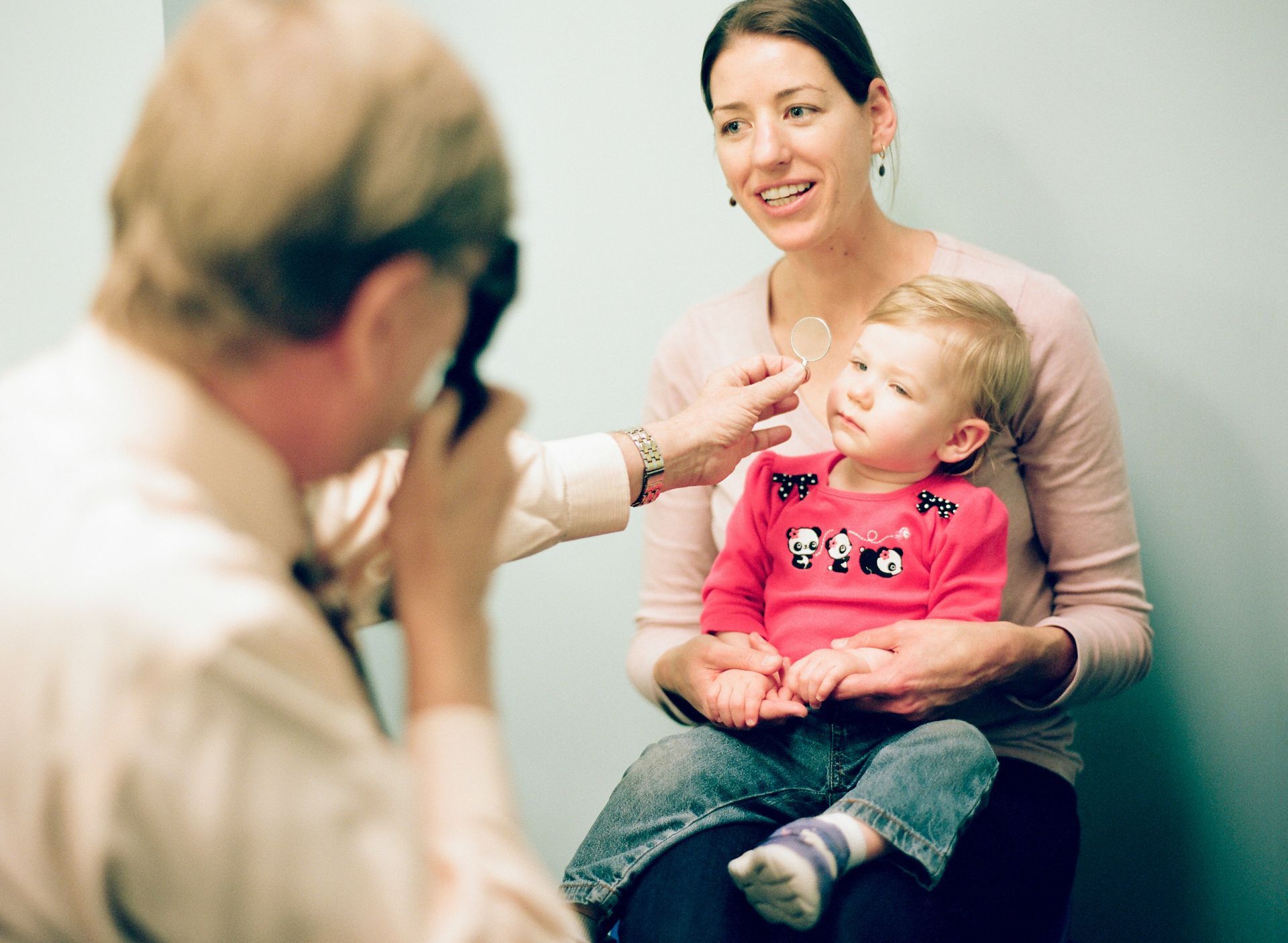 girl sitting on mother's lap receiving eye test
