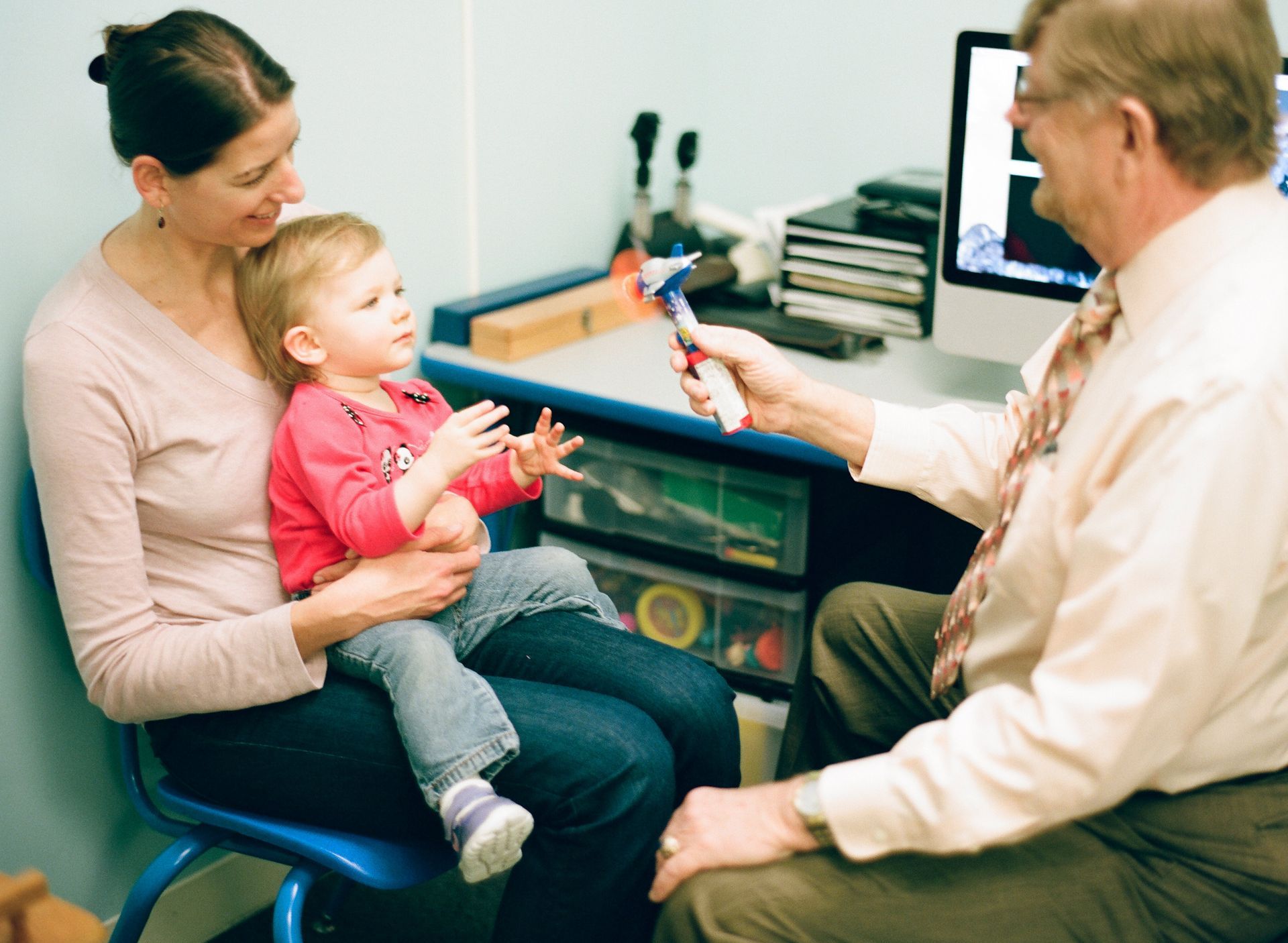 girl sitting on mother's lap receiving eye test