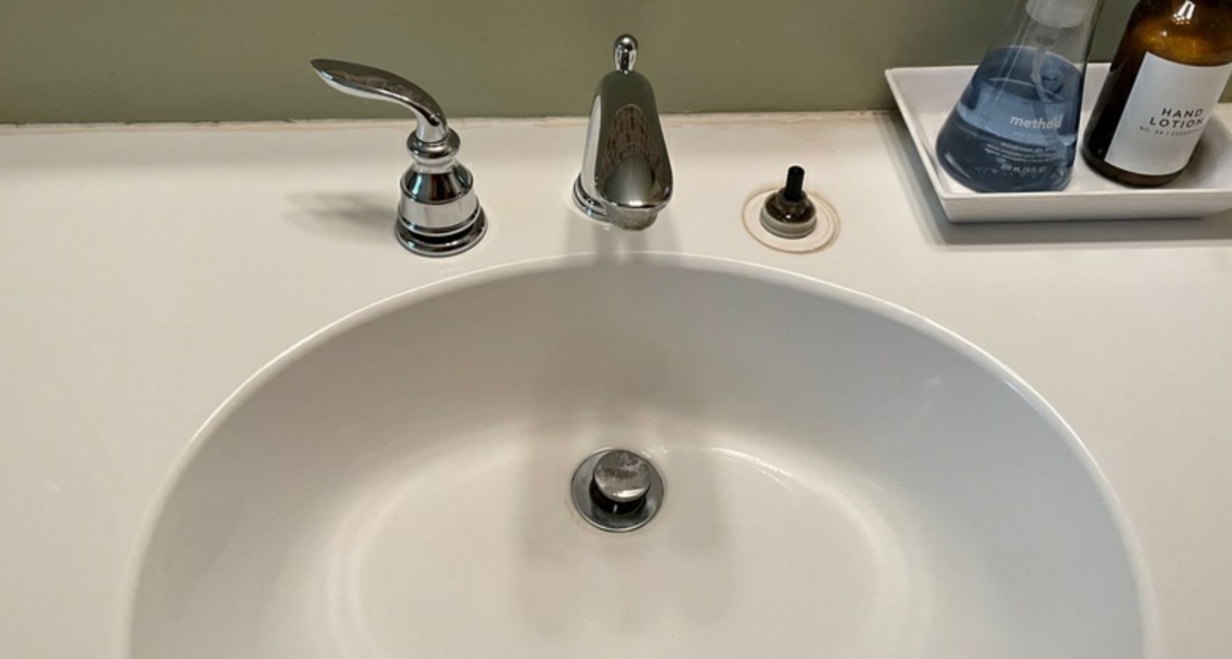 A bathroom sink with a faucet and a bottle of soap on the counter.