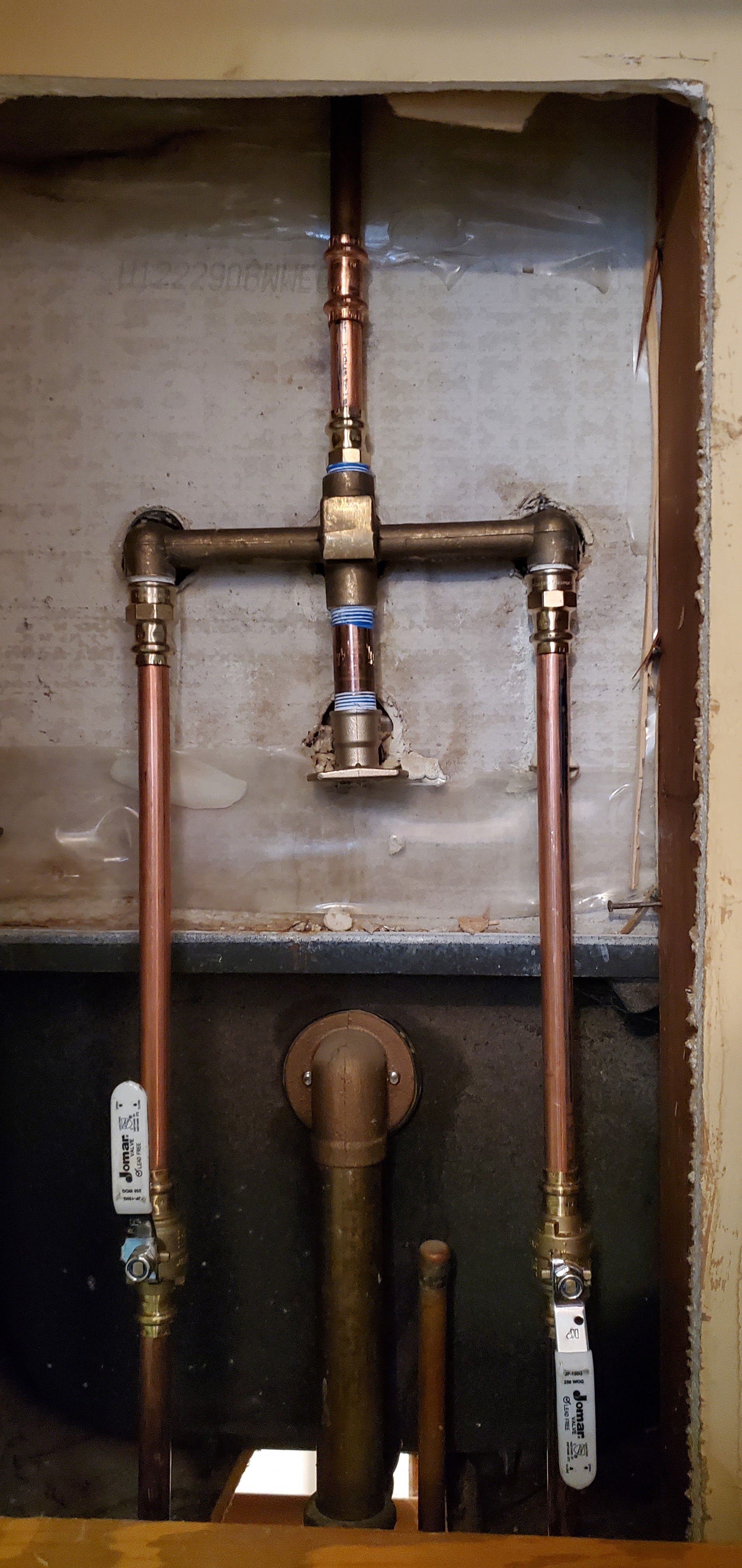 A close up of a copper pipe in a wall.