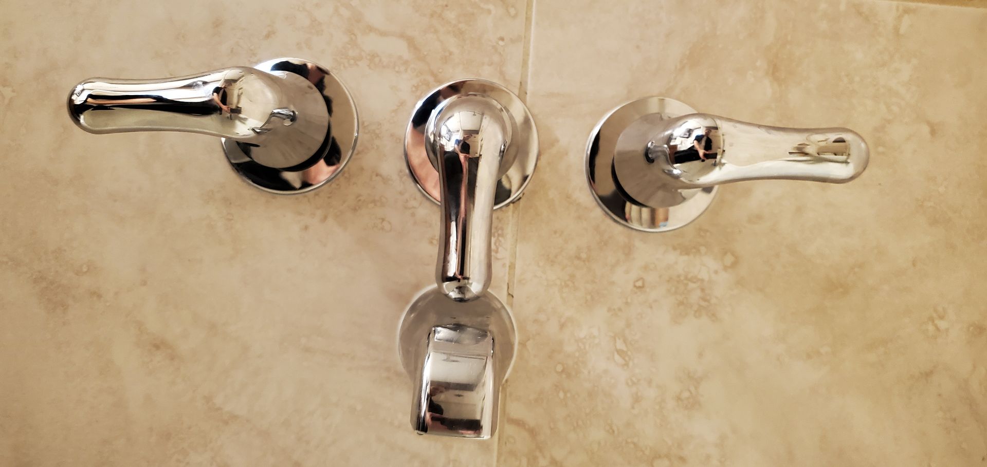 A close up of three chrome shower faucets on a tiled wall.