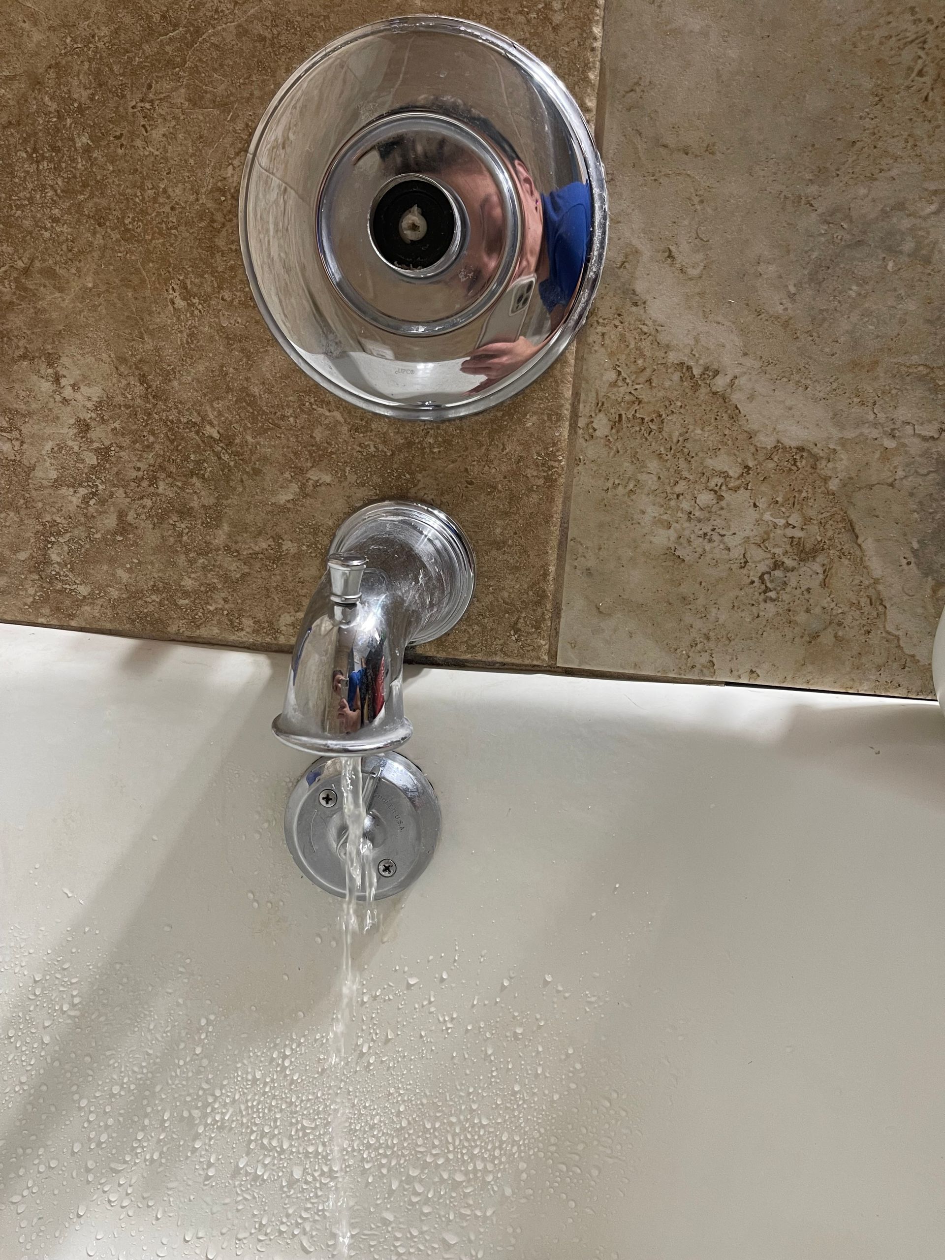 A close up of a bathtub faucet with water running out of it.
