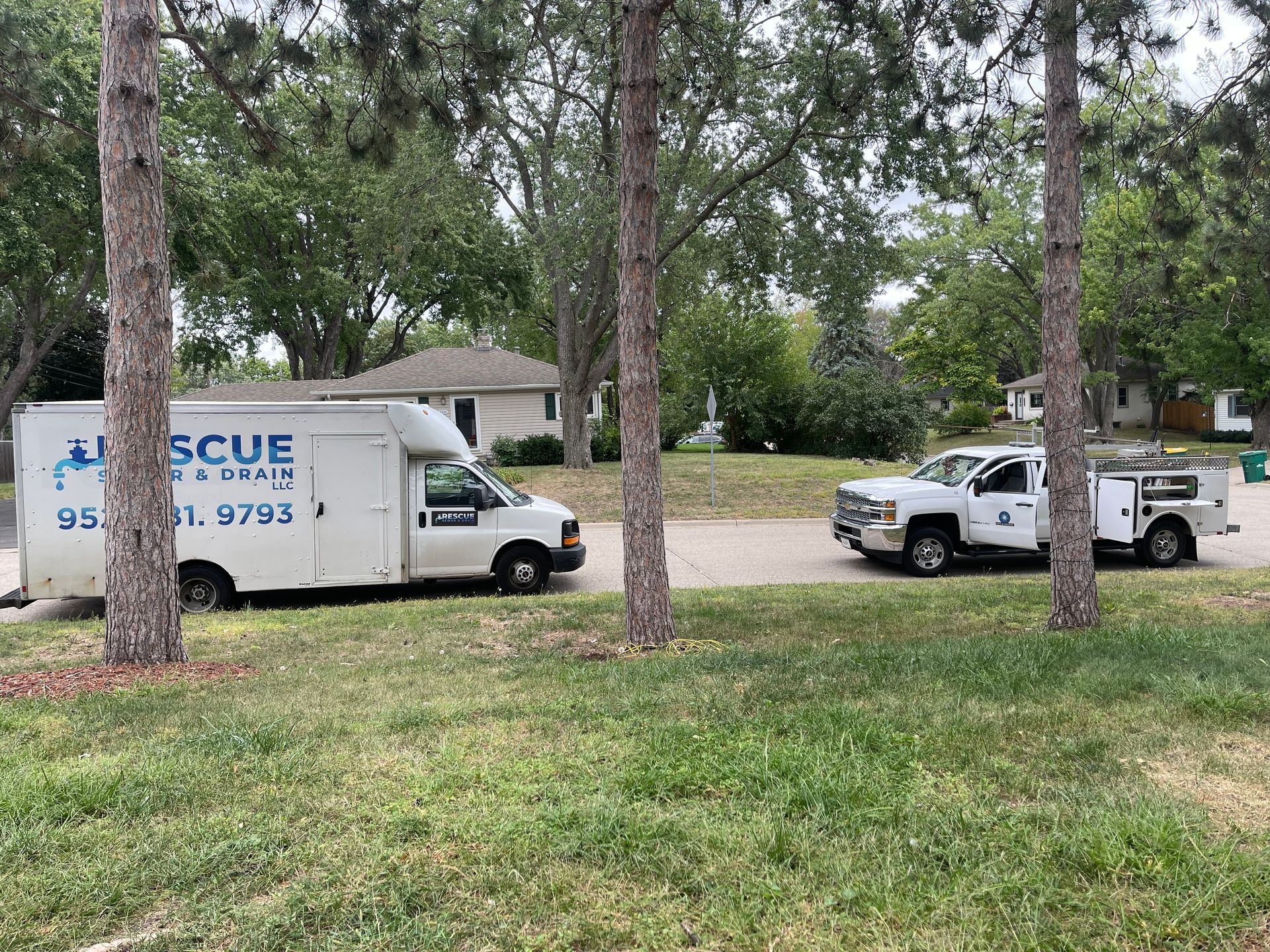 Two trucks are parked next to each other in a grassy area.