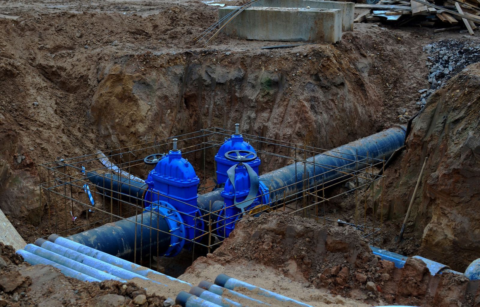 Blue water main valves installed in a trench at a construction site.