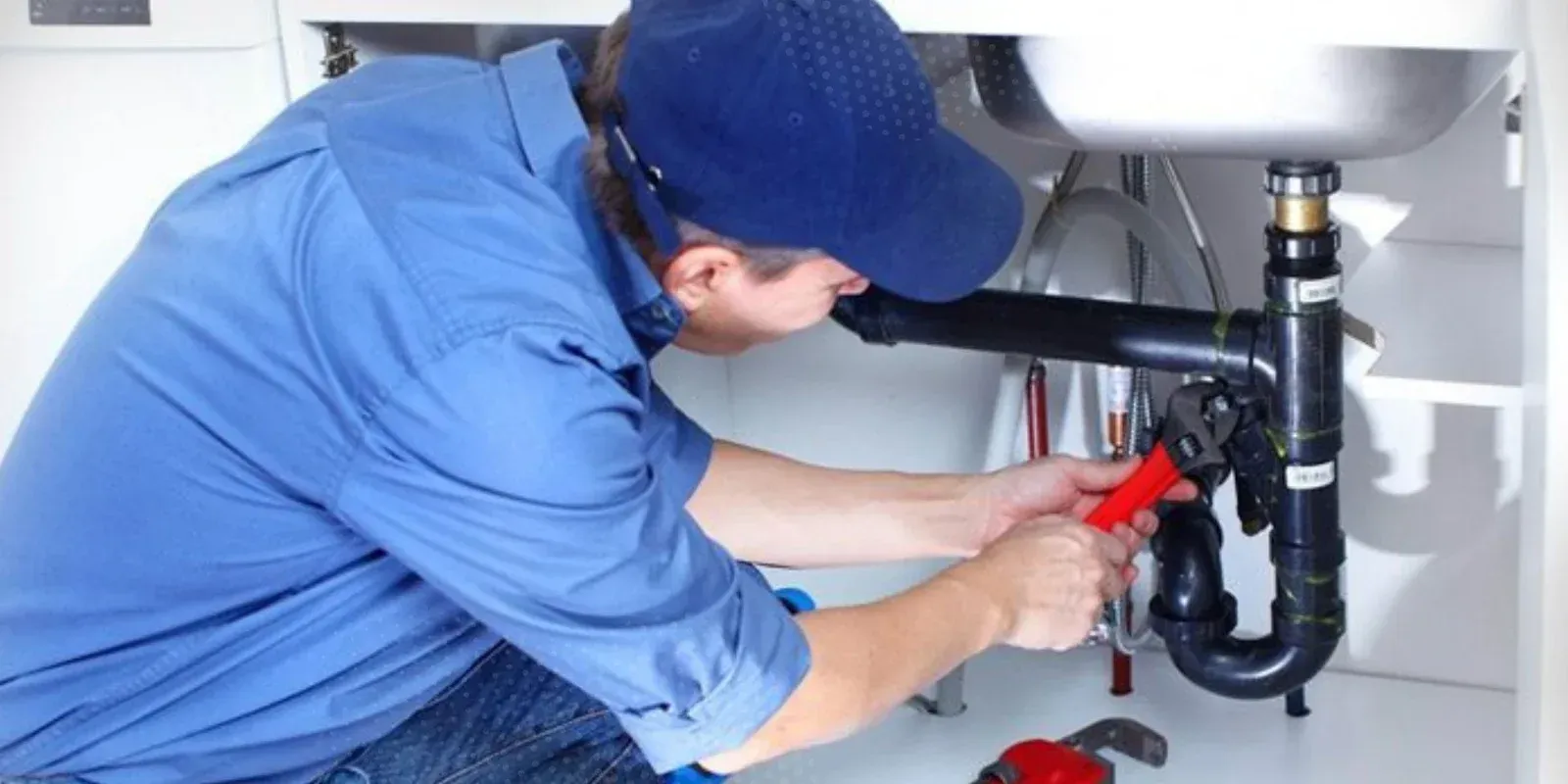 Black irrigation pipes with blue connectors in a trench, ready for installation in the ground.