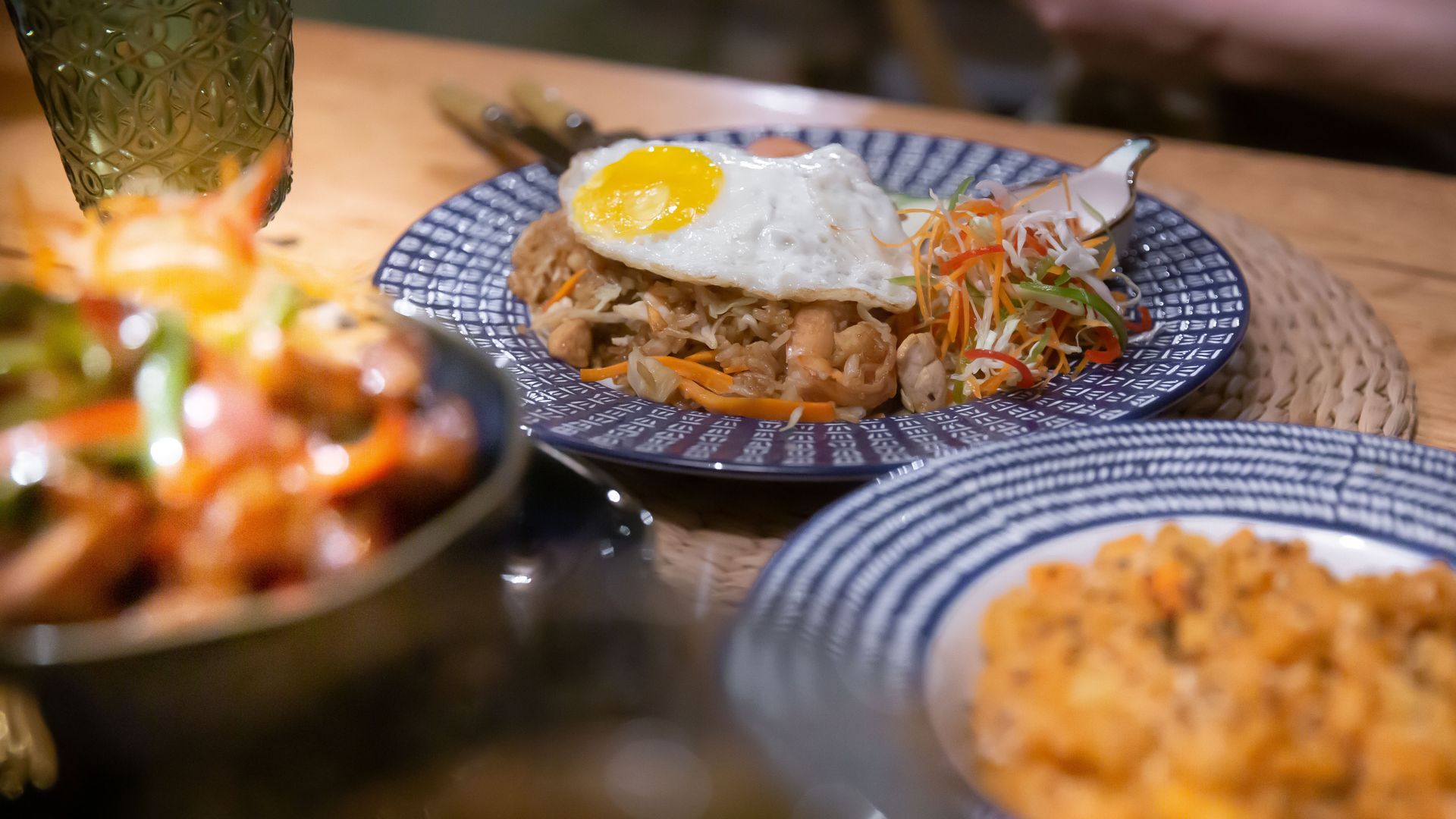 Three plates of food are sitting on a wooden table.
