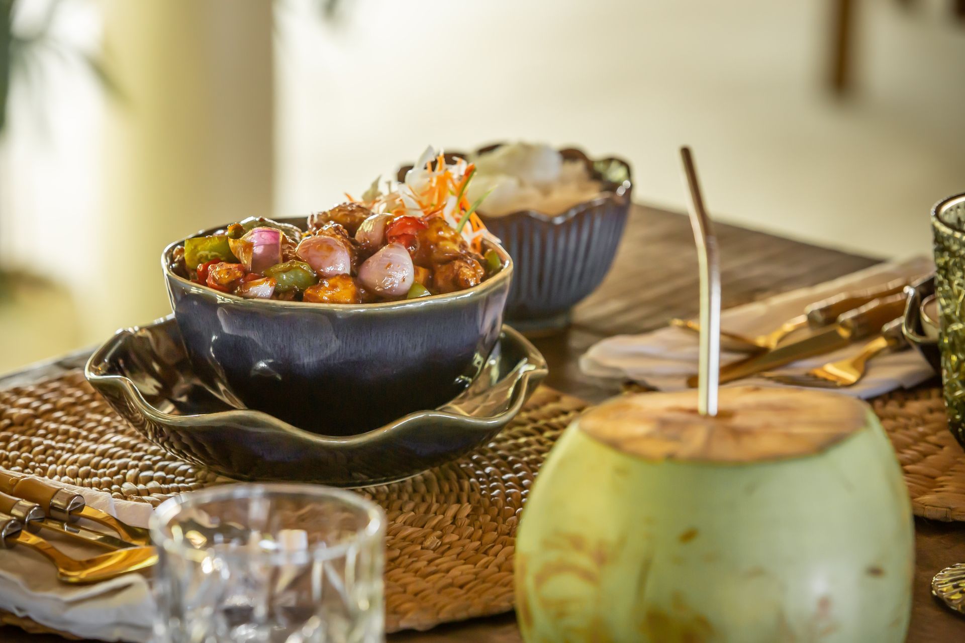 A bowl of food is sitting on a table next to a coconut.