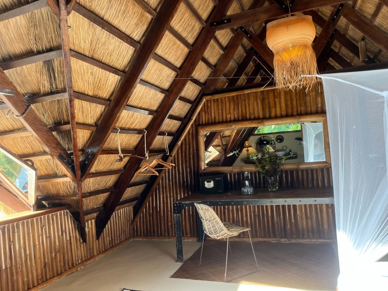 A room with a thatched roof and a desk and chairs