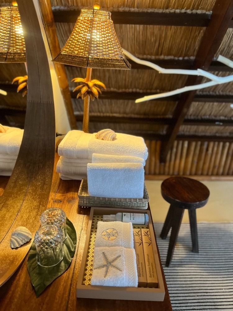 A bathroom with towels , soap , glasses and a stool.