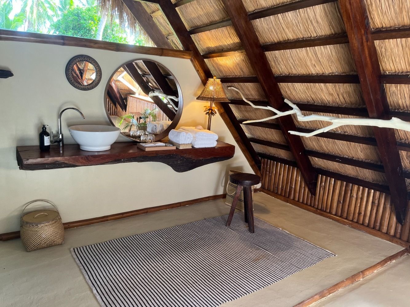 A bathroom with a thatched roof and a sink