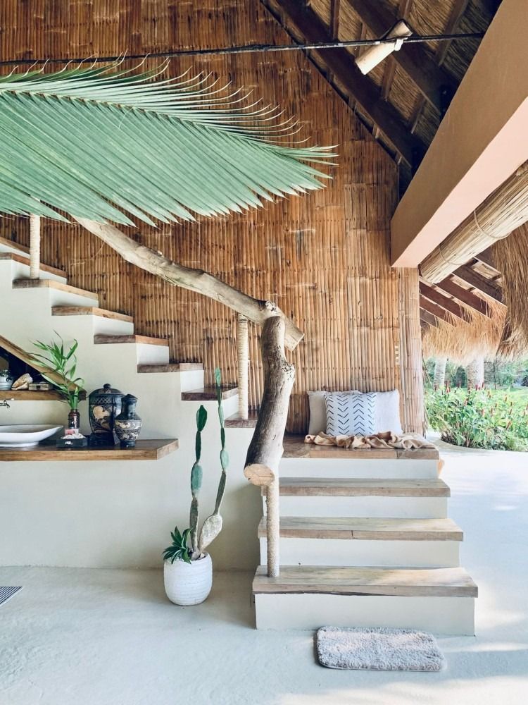 A house with a thatched roof and stairs leading up to it.
