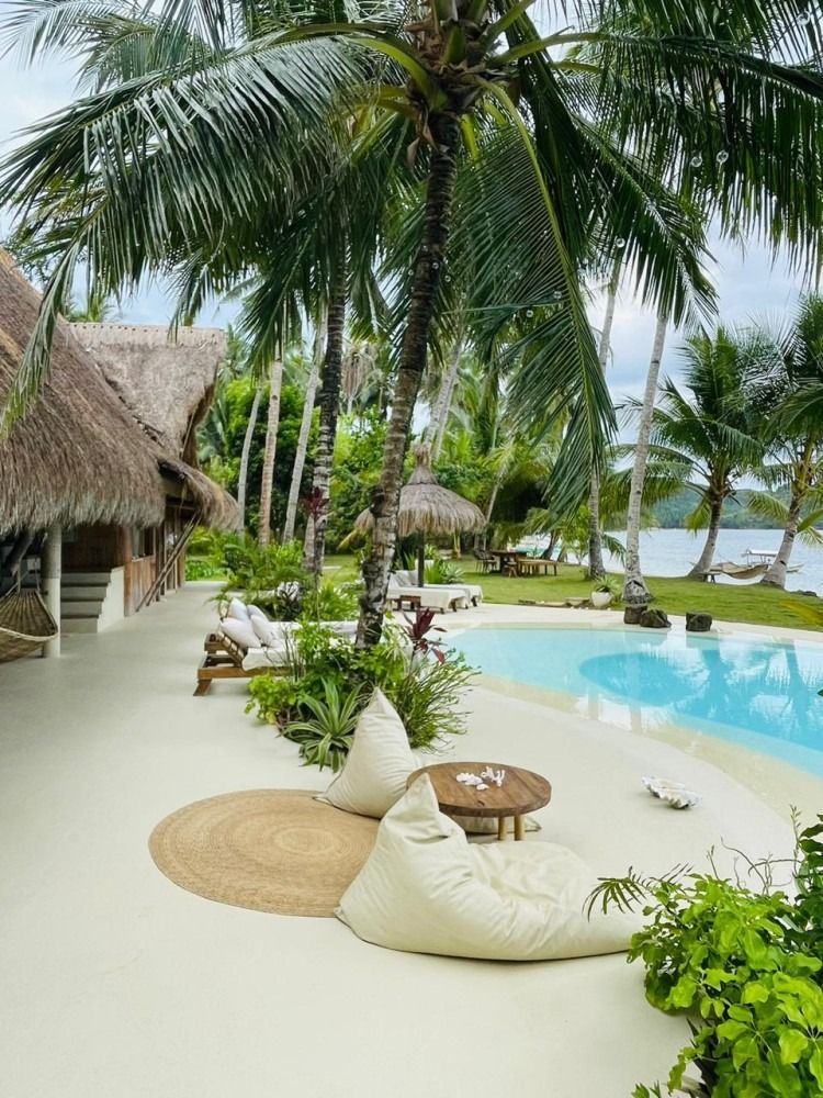 A swimming pool surrounded by palm trees and a table and chairs.