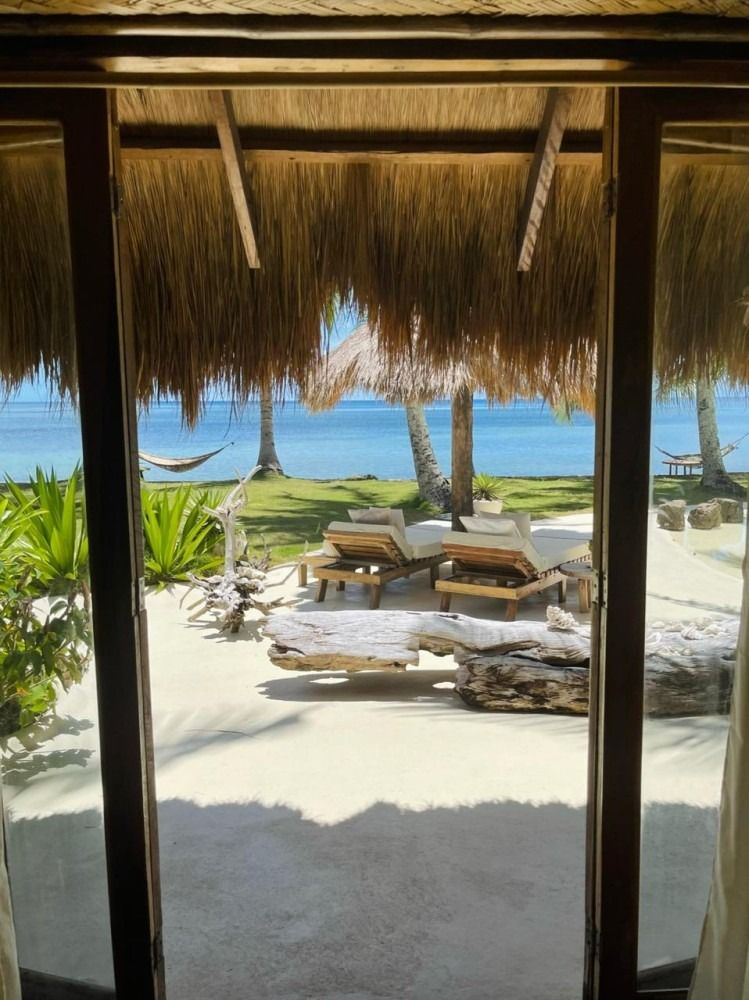 A view of the ocean from a room with a thatched roof