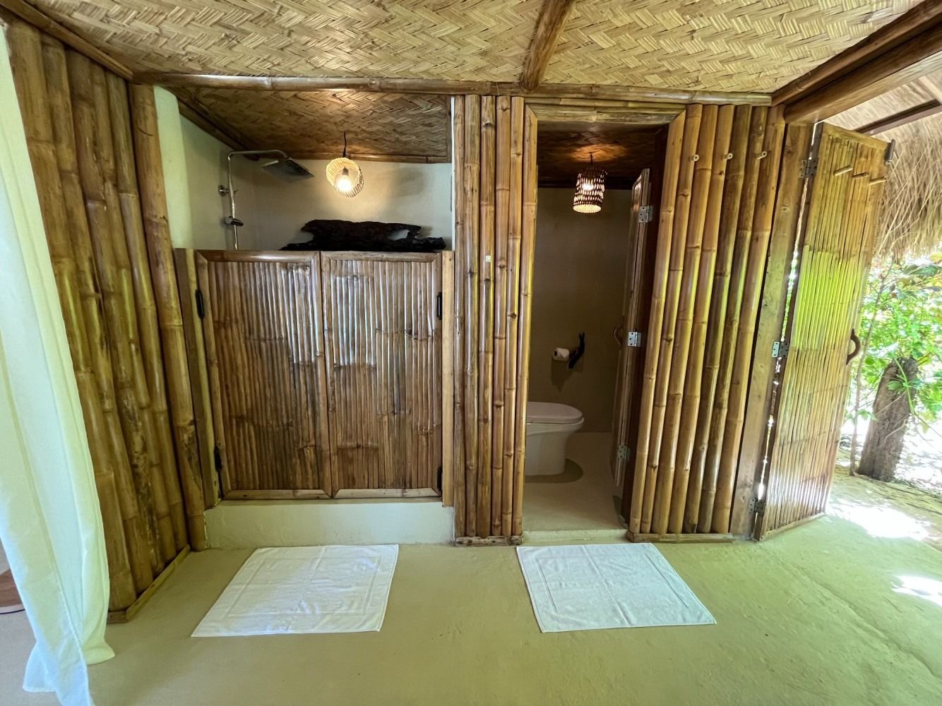 A bathroom in a bamboo hut with a toilet and shower.