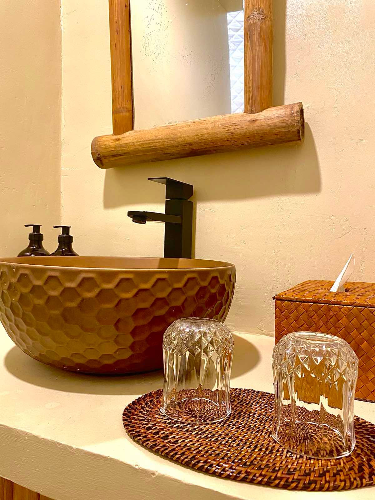 A bathroom with a sink , mirror and glasses on the counter.