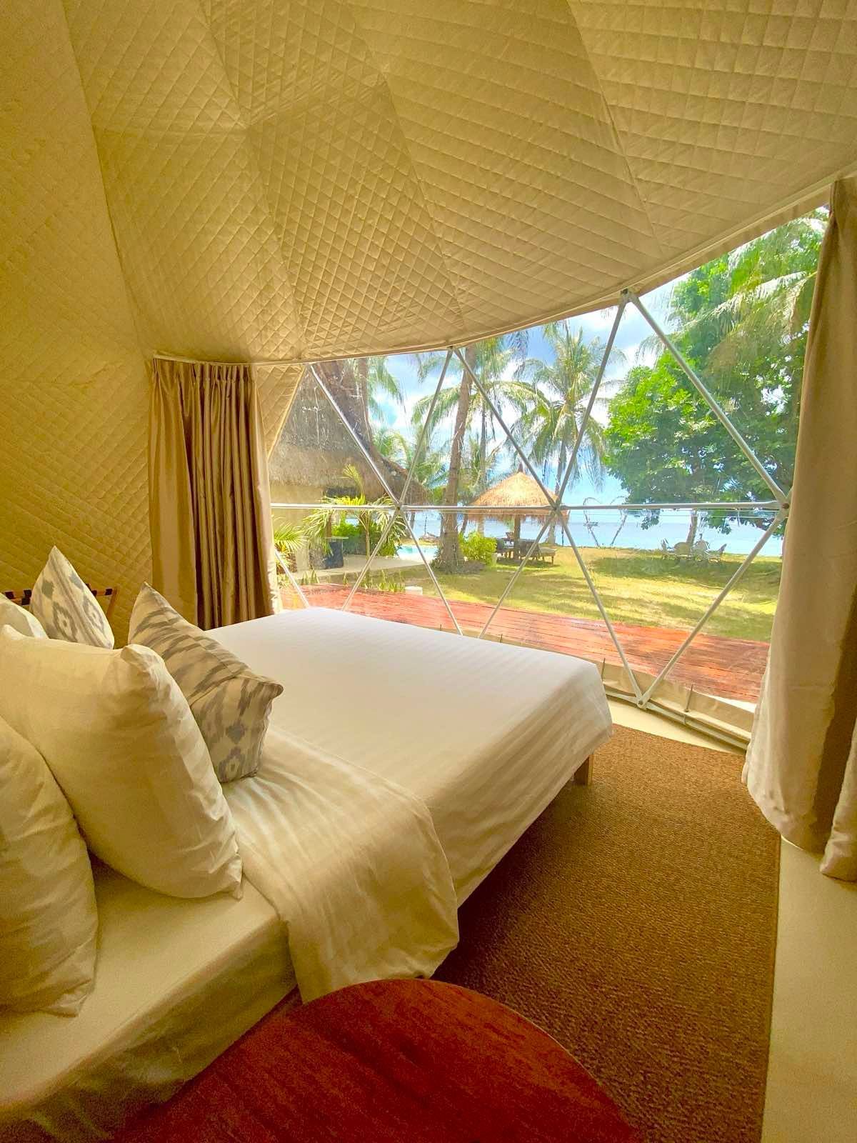 A bedroom with a bed and a large window with a view of the ocean.