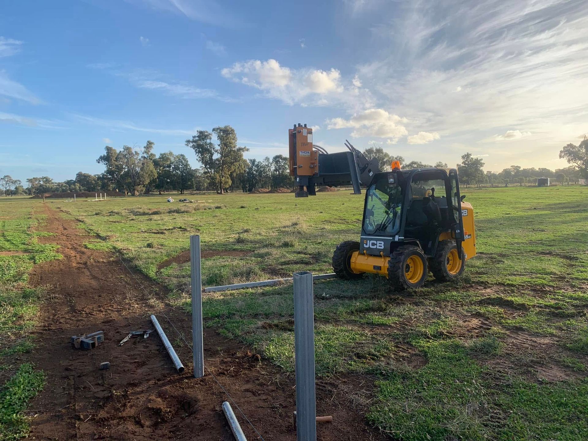 A yellow tractor is driving through a grassy field.