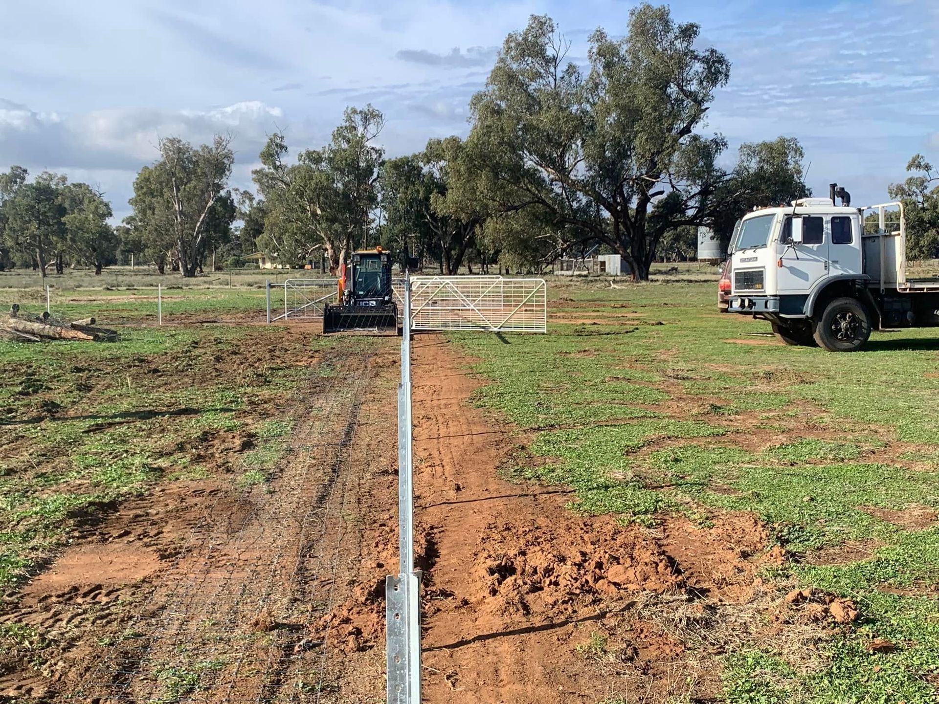 A truck is parked on the side of a dirt road in a field.
