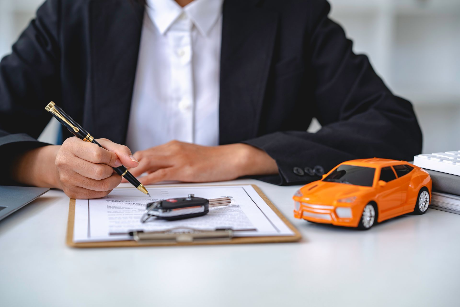 An agent reviewing car insurance paperwork beside keys and a model car.