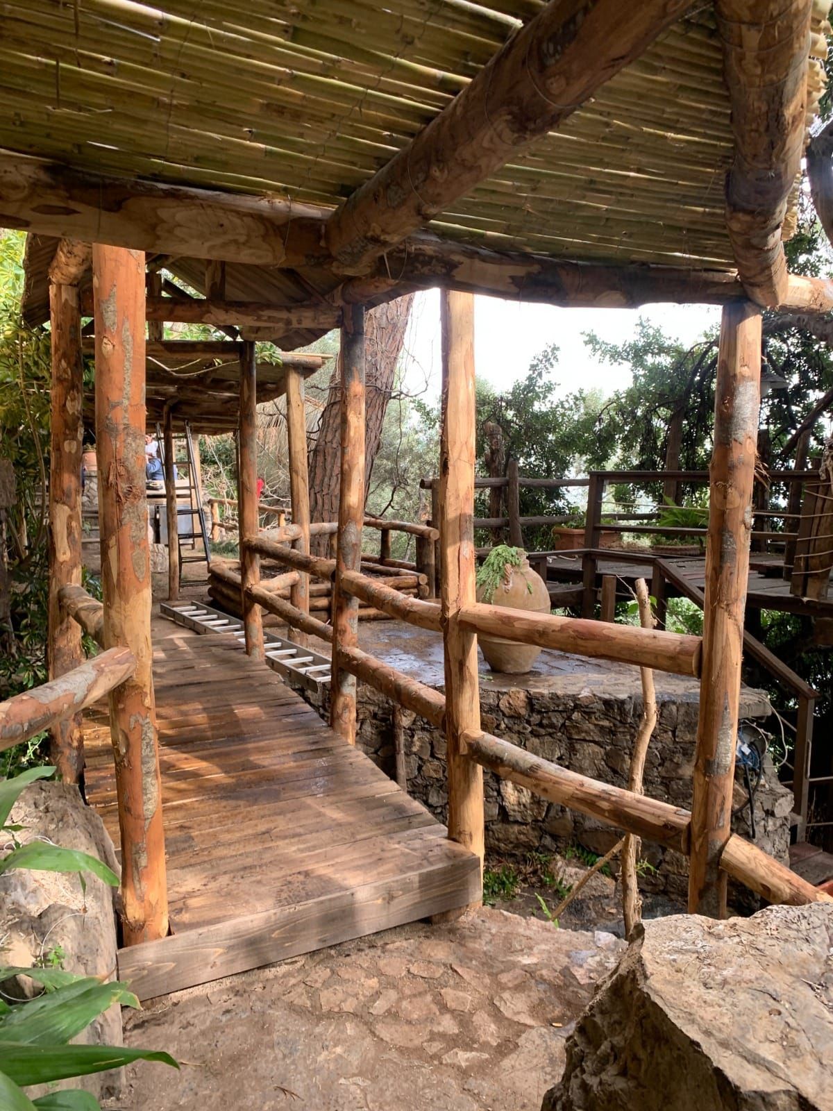 Passerella in legno con ringhiera e tetto rustici, con vista su un paesaggio verde.