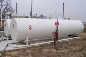 Two large white tanks are sitting next to each other in a field.