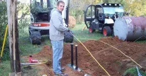 A man is standing in a pile of dirt next to a tractor.