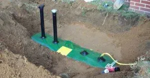 A green tarp is sitting on top of a pile of dirt in a hole.