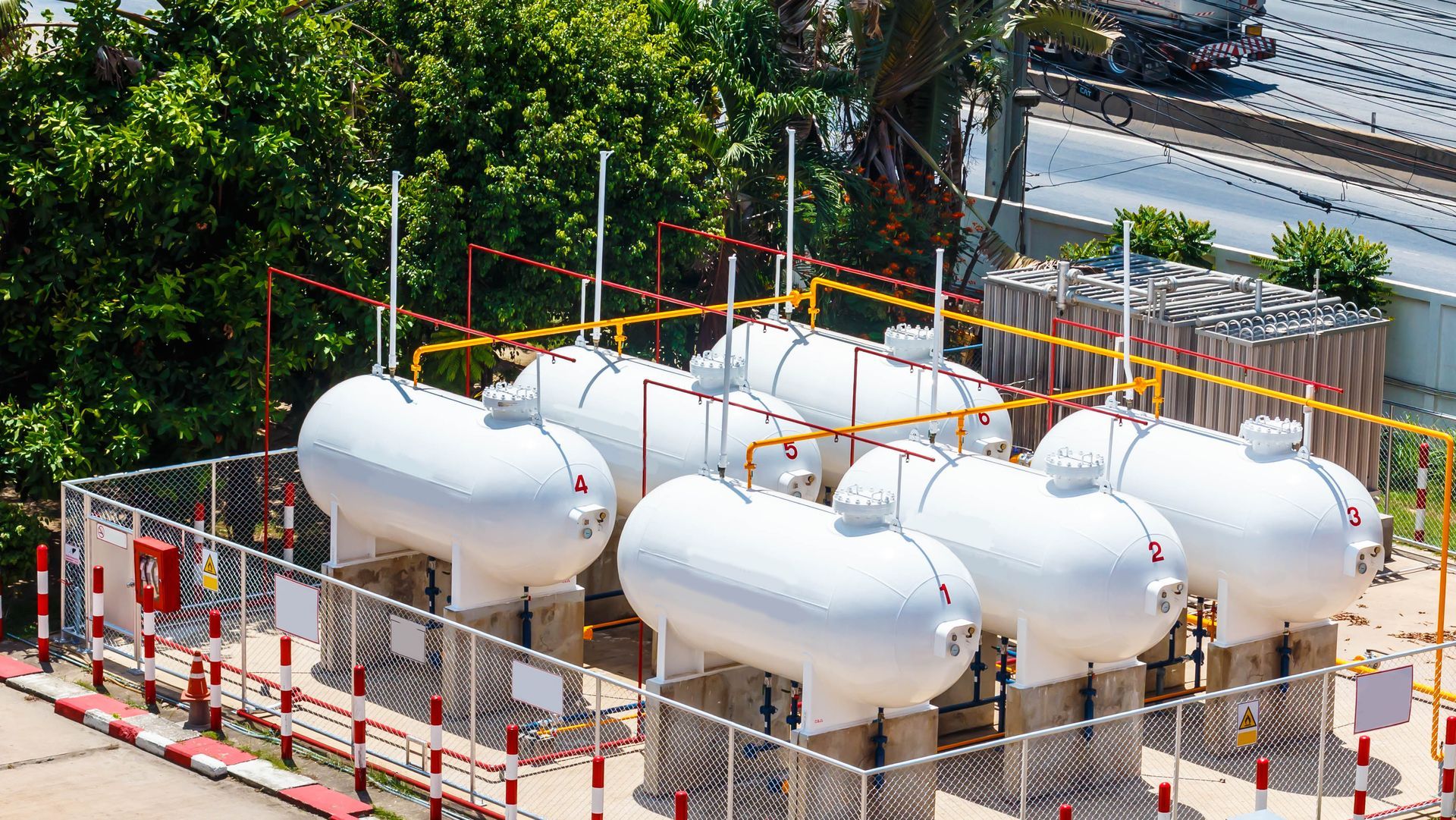 A row of white tanks sitting next to each other in a fenced in area.