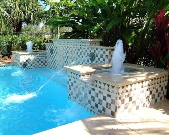 Tropical pool with blue water and tiled fountains surrounded by lush greenery