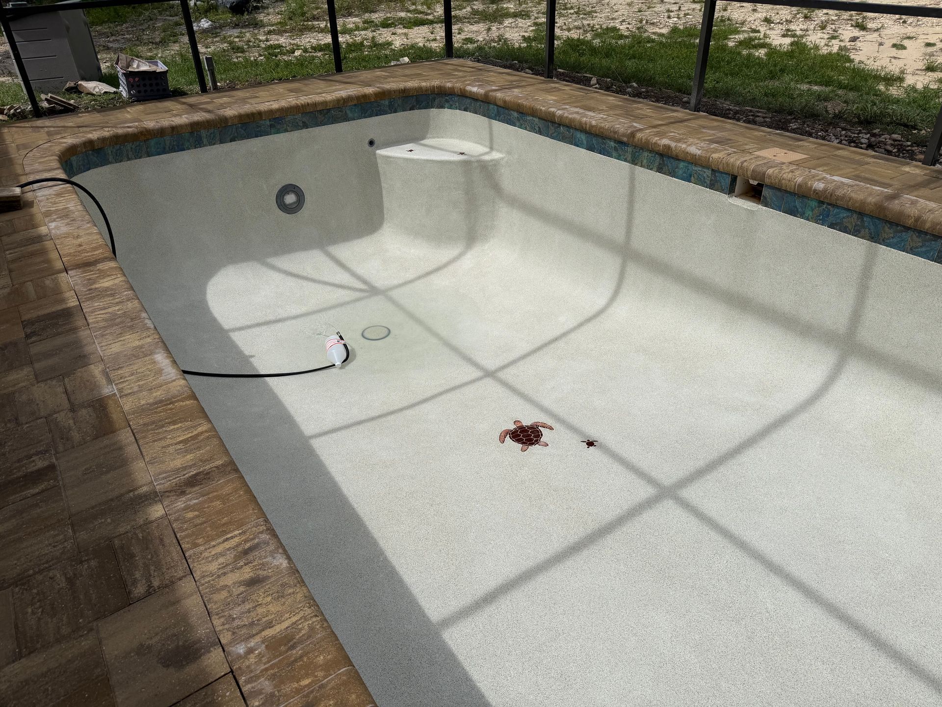 Empty white swimming pool with a curved deep end and brick patio edge