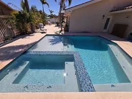 Backyard swimming pool with a shallow spa area, blue water, and a patio beside a house