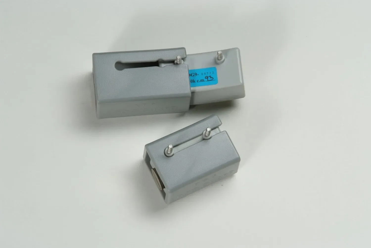 Two grey metal mechanical sliding components on a plain white surface.