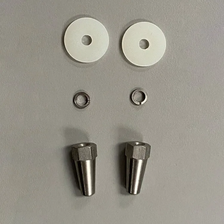 Two white plastic washers, two metal lock washers, and two stainless steel tapered decorative nuts on a gray surface.