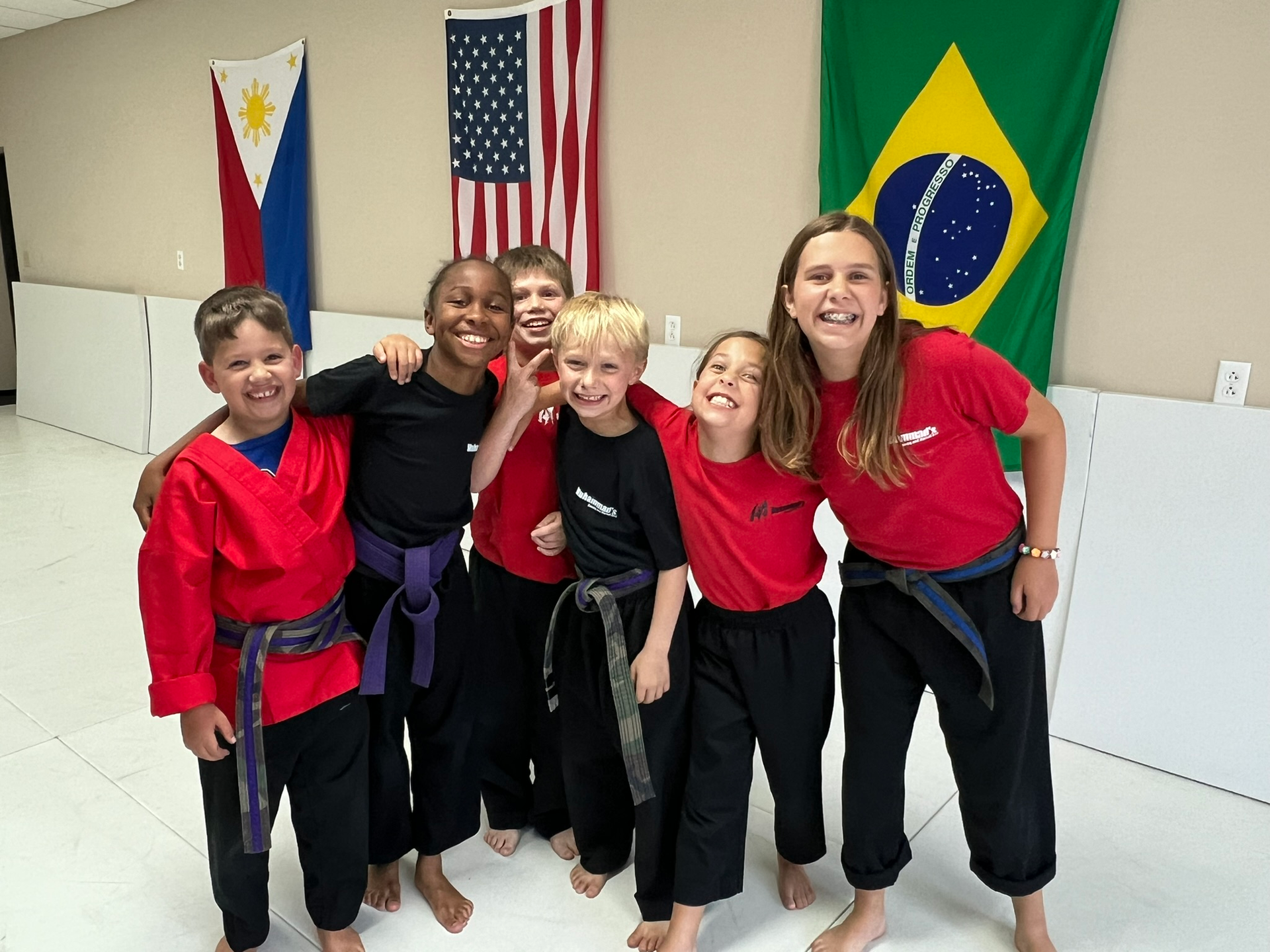 A group of children are posing for a picture in front of flags.