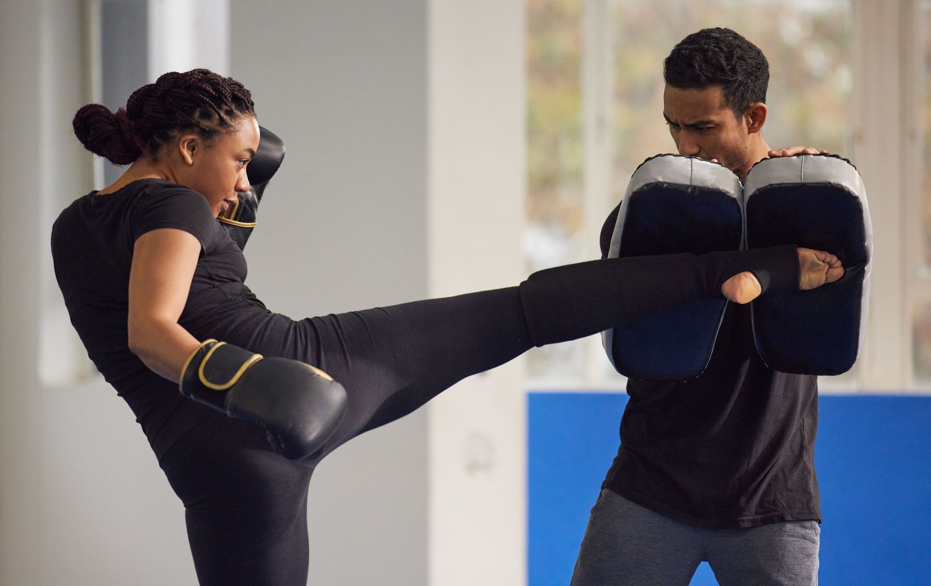 A man and a woman are practicing martial arts in a gym.