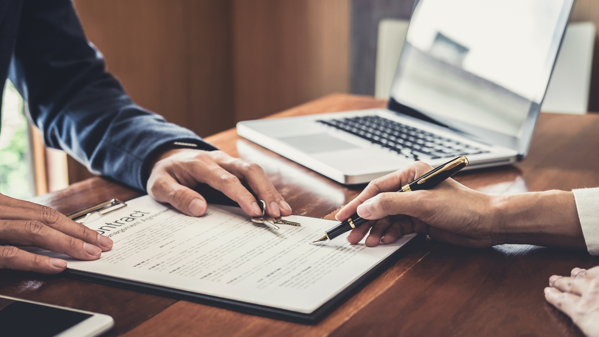 一個男人和一個女人正在木桌上簽署一份文件。