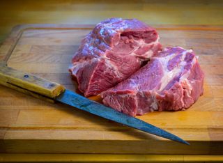 Heart shape Raw fresh meat Porkbut with knife, on wooden slate background.