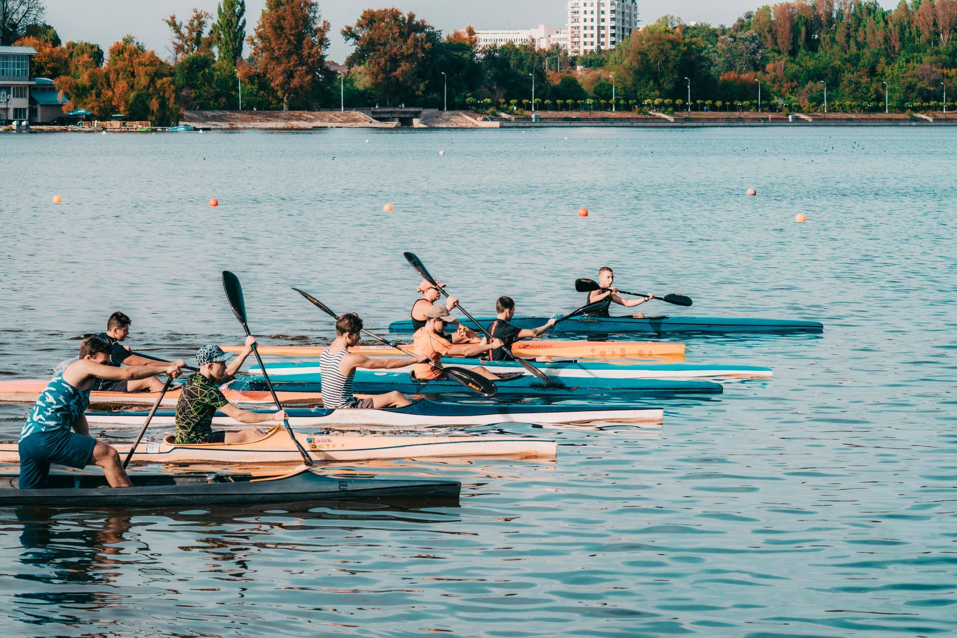 Canoe race in progress on a lake; several boats are side-by-side with paddlers, supported by a wooden dock.