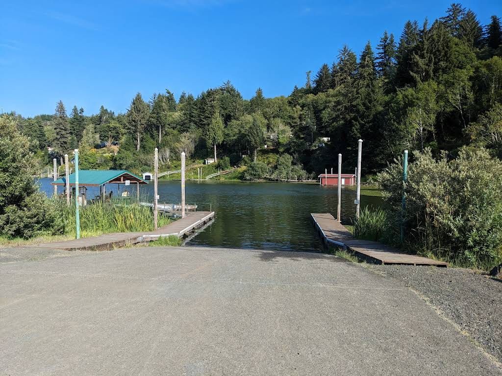 Boat launch into a lake, with docks on either side. Green trees and a blue sky in the background.