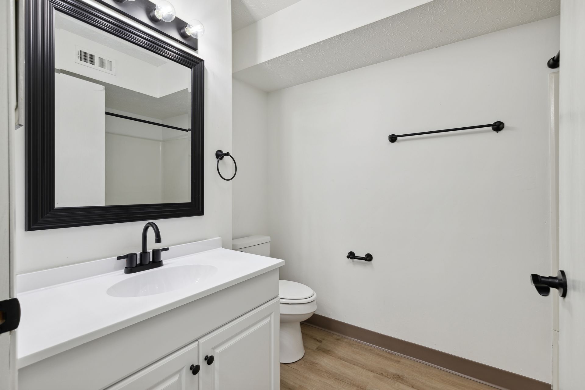 A bathroom with a sink , toilet , mirror and towel rack.