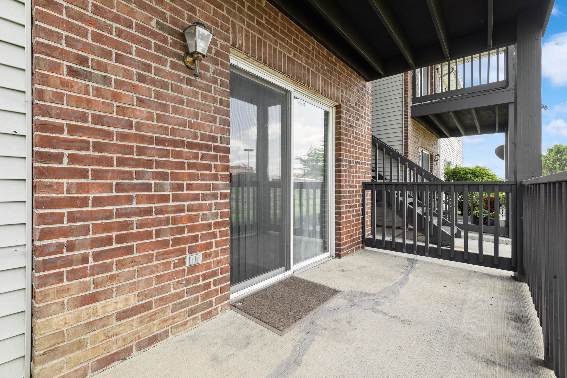 A brick building with a sliding glass door and a balcony.