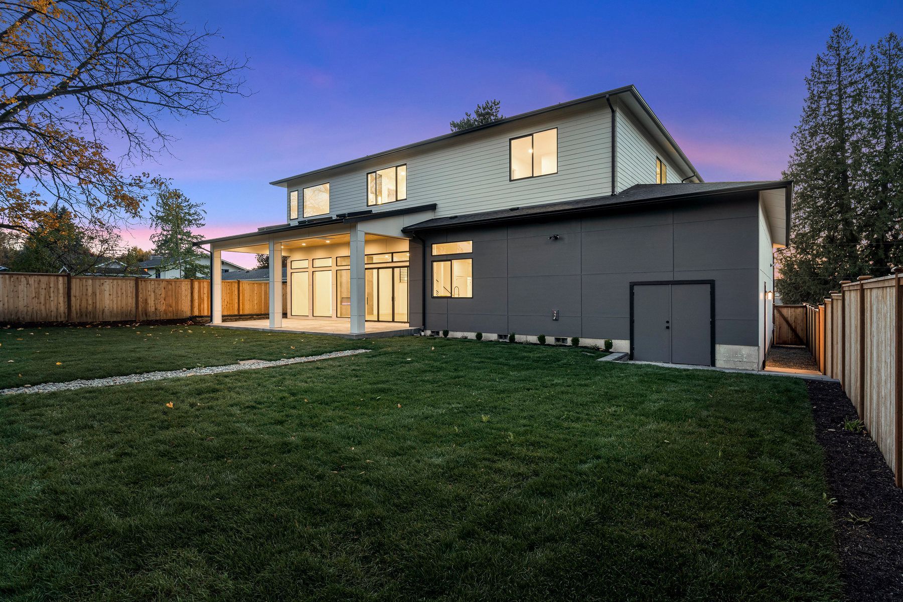 The backyard of a house with a large lawn and a fence.