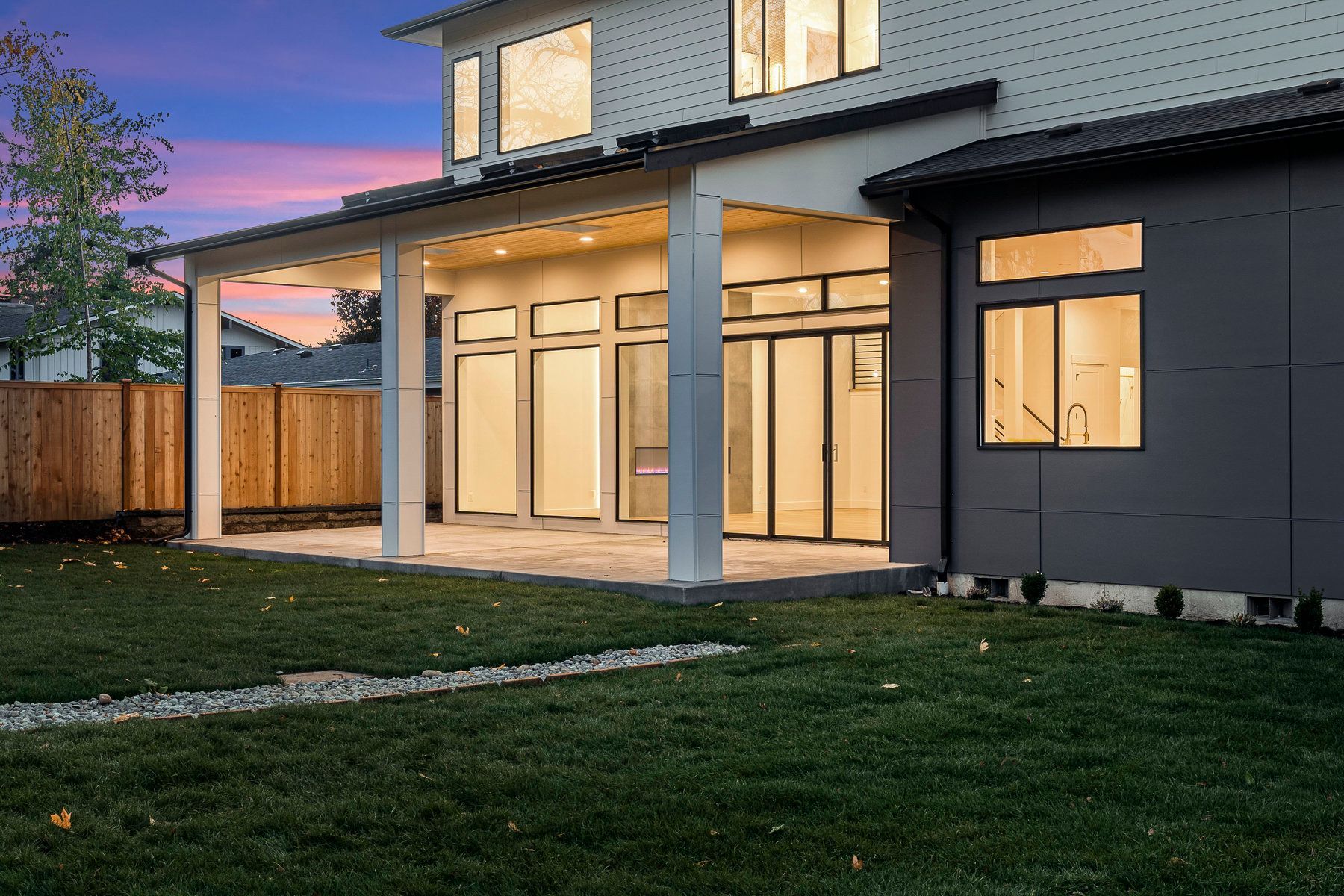 The backyard of a house with a covered patio and a fence.