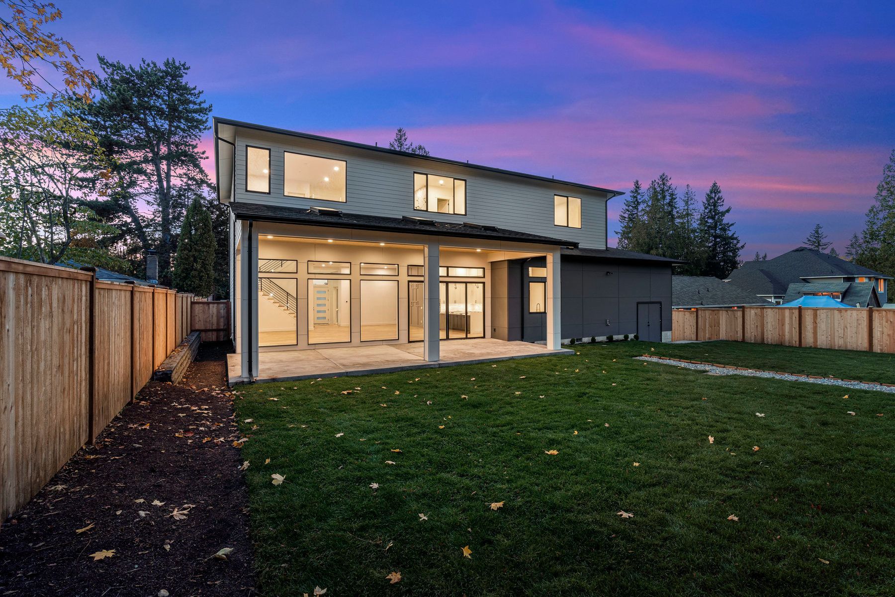 The back of a house with a large lawn and a wooden fence.