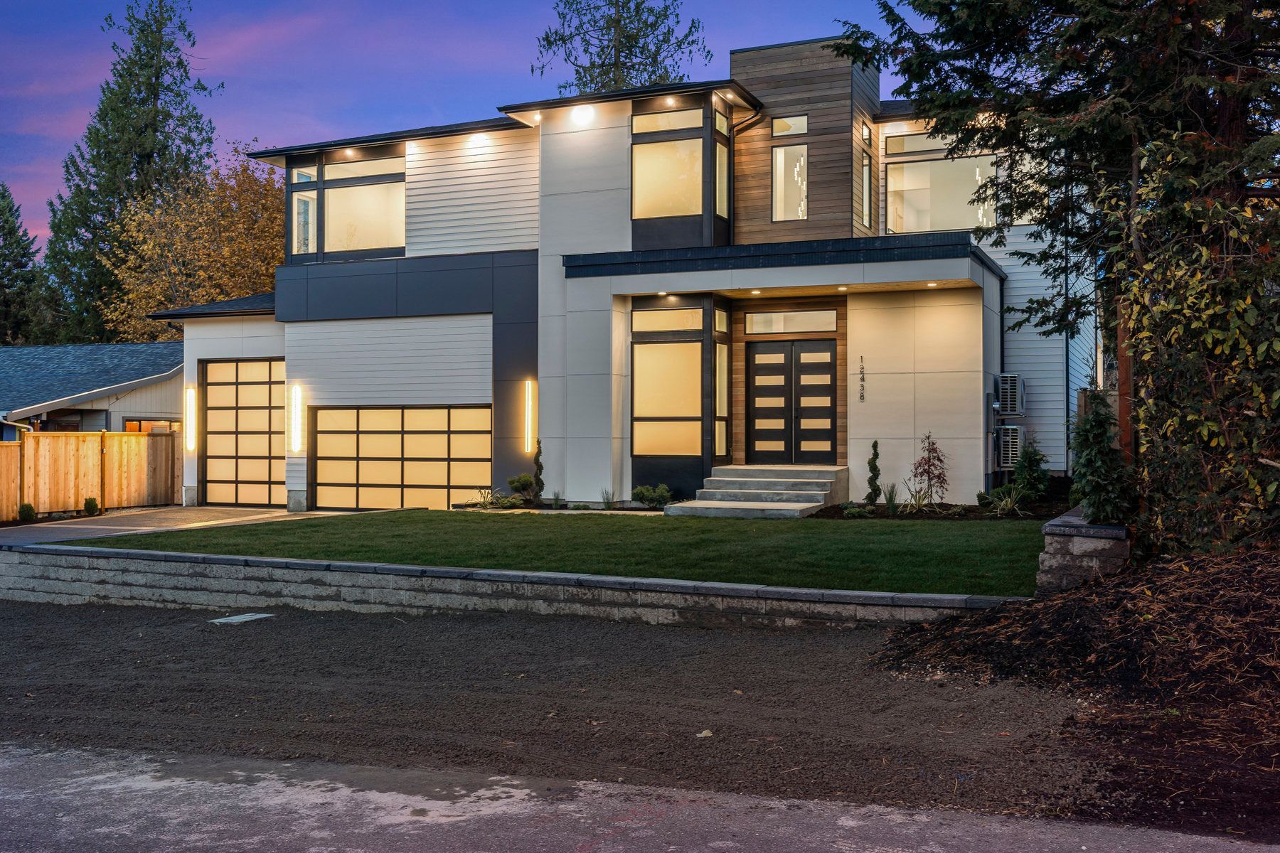 A large modern house is lit up at night.