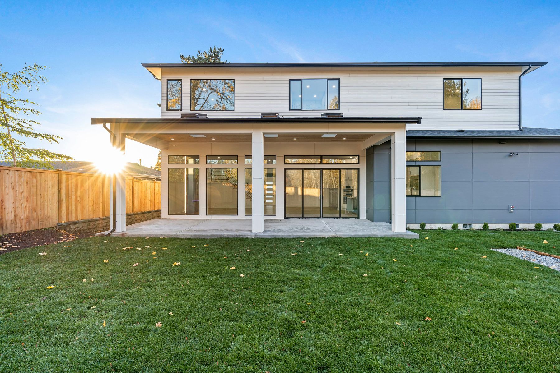 The back of a large house with a large lawn in front of it.
