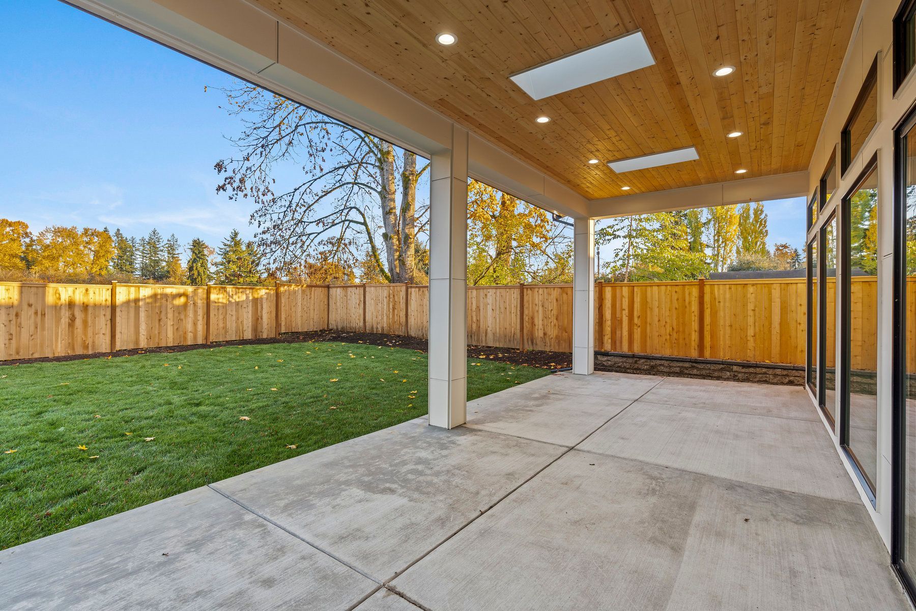 A large patio with a wooden fence in the backyard of a house.
