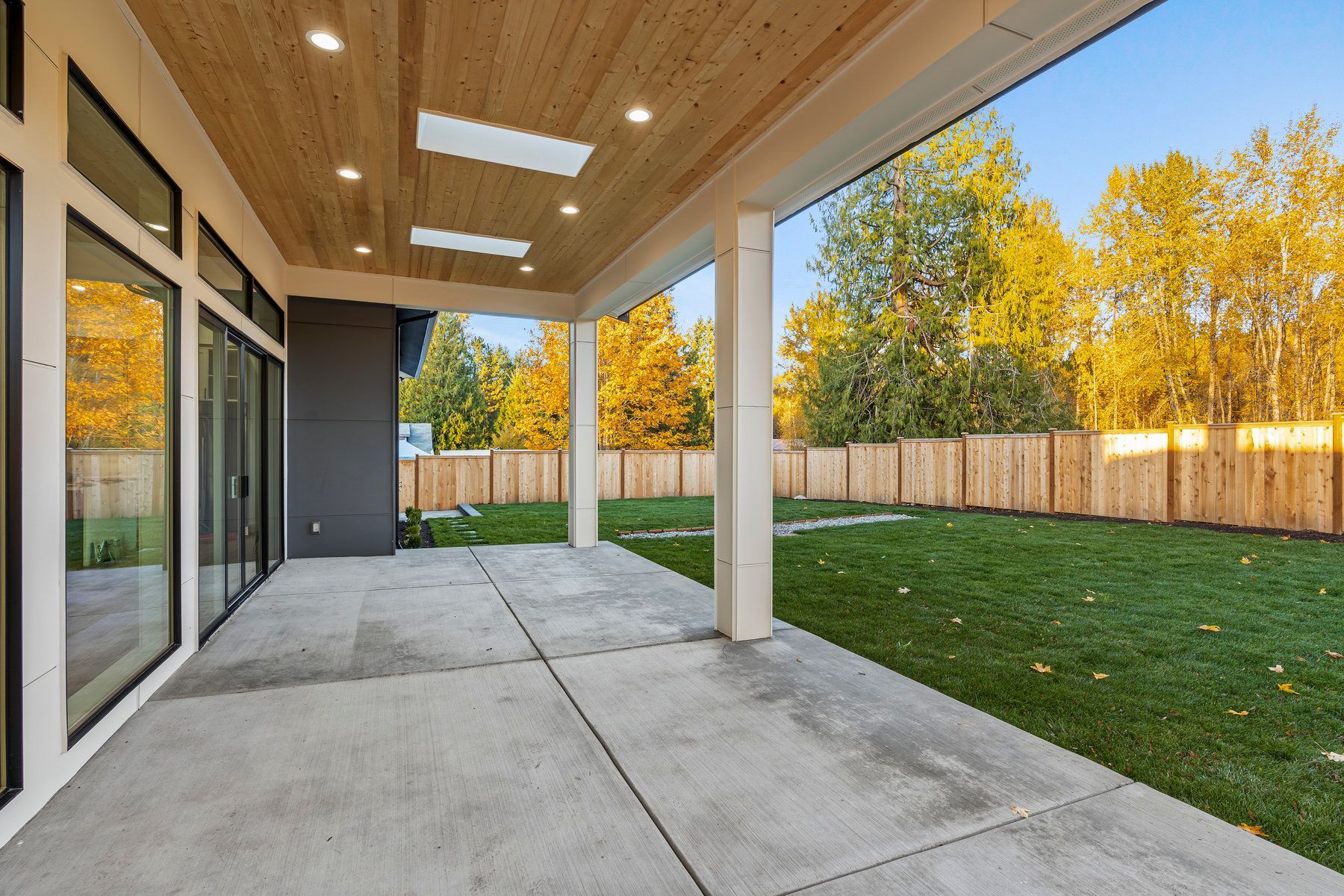 A large patio with a wooden ceiling and a fence in the background.