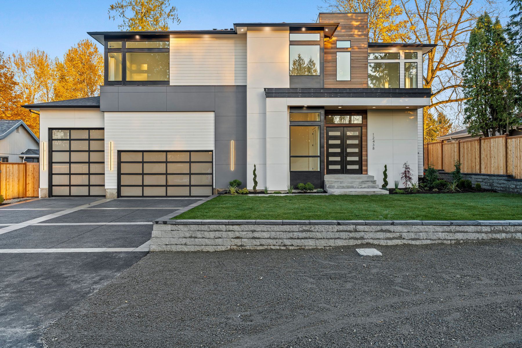 A modern house with a large garage and a fence in front of it.