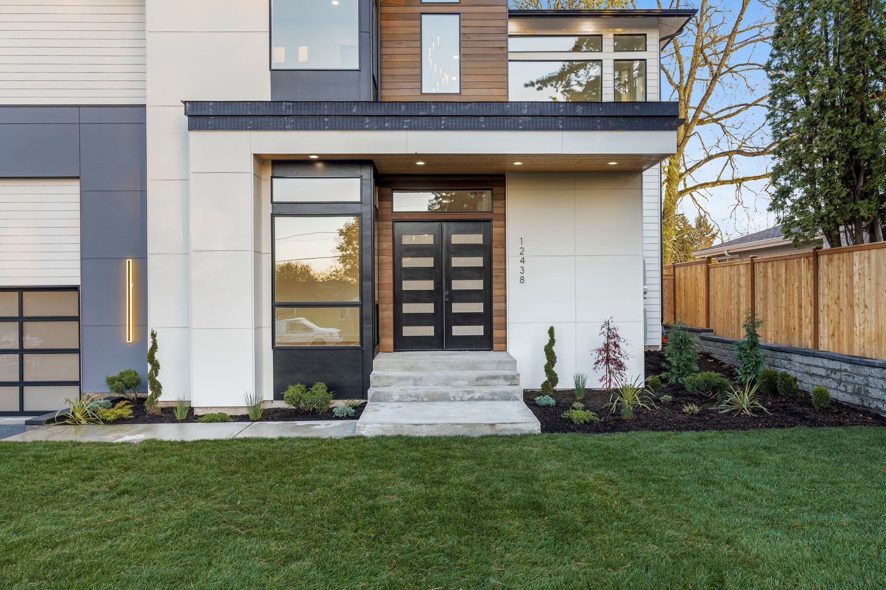 The front of a modern house with a large lawn in front of it.